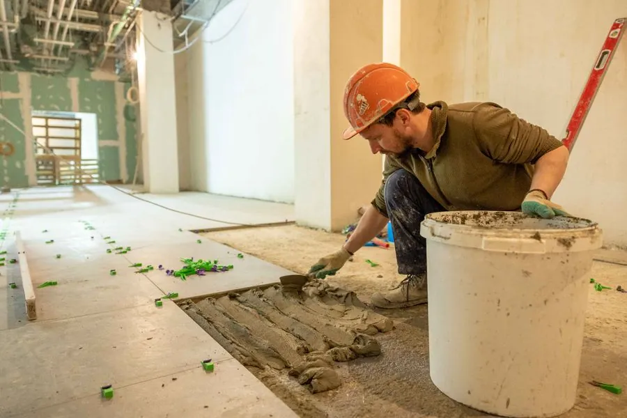 AS Home Solutions MD installer in a hard hat setting flooring on site